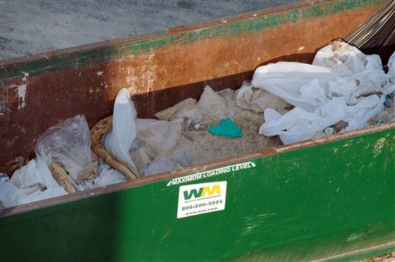 Soiled, oil-absorbing boom and other debris sit in an open, improperly lined waste container in Orange Beach, Ala., on June 17.